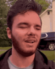 a man with a beard is making a funny face with his eyes closed