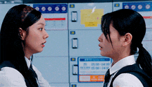 two girls are standing next to each other and looking at each other in front of lockers .