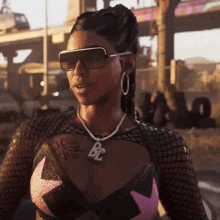a woman wearing sunglasses and a necklace with a pendant that says be