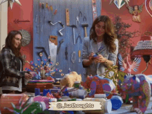 two women are standing in front of a table with a sign that says @isathoughts on it
