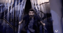 a man with a beard and headphones is jumping through a window .