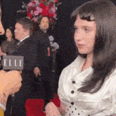 a woman is being interviewed by a man with a sign that says elle in the background