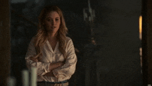 a woman with her arms crossed is standing in a dark room .