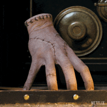 a close up of a hand with stitches and a netflix logo behind it