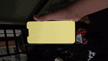 a person is holding a cellphone with a yellow screen
