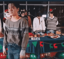 a group of people are standing around a table with food on it .