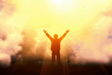 a silhouette of a man with his arms outstretched in front of the sun