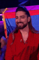 a man with long hair and a beard waves his hand