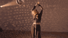 a woman in a black dress is dancing in a dark room with polka dots on the wall .