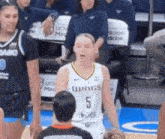 a female basketball player with the number 5 on her jersey stands on the court