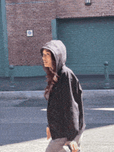 a woman in a black hoodie walks down a street