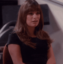 a woman with long hair and bangs is wearing a black top