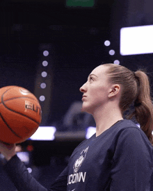 a woman wearing a blue shirt that says iconn holds a basketball