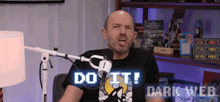 a man is sitting in front of a microphone with the words do it dark web behind him