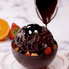 chocolate is being poured over a chocolate bowl filled with fruit