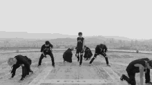 a black and white photo of a group of people dancing on top of a building .