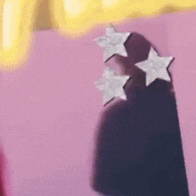 a close up of a person wearing a pair of earrings with three stars on them .