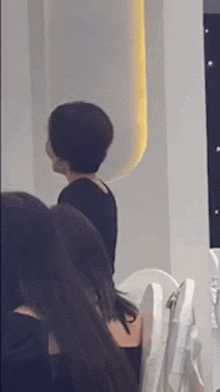 a woman with short hair is sitting in a row of chairs in a room .