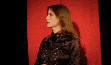 a woman in a black shirt is standing in front of a red background