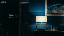 a dark room with a lamp and a picture on the wall that says bbc