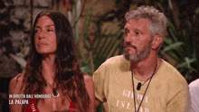 a man and a woman are sitting next to each other in front of a sign that says in diretta dall honduras la palapa