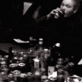 a man is sitting at a table surrounded by bottles and cans of alcohol .