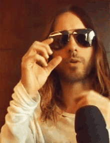 a man with long hair is wearing sunglasses and giving a peace sign