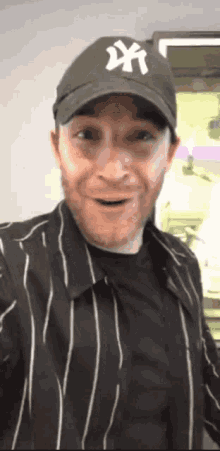 a man wearing a ny hat and a striped shirt