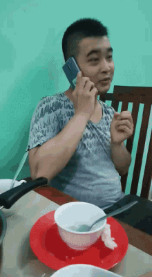 a man is talking on a cell phone while sitting at a table
