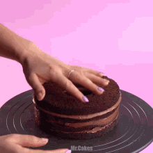 a woman 's hand is reaching into a chocolate cake on a black plate that says mr.cakes on the bottom