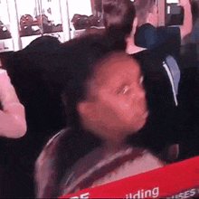 a little girl is sitting in a crowd of people and looking at the camera .