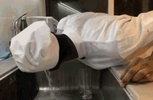 a man in a chef 's hat is washing dishes in a sink
