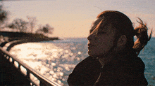 a woman in a ponytail is looking at the ocean