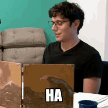 a man wearing glasses sits at a table with a screen that says ha