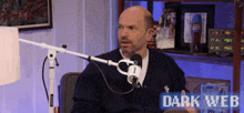 a man sitting in front of a microphone with the words dark web on the bottom right