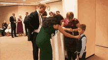 a man and a woman are standing next to each other in a room . the woman is wearing a green dress .