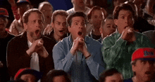 a group of people are sitting in a stadium watching a game and making funny faces .