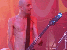 a shirtless man playing a fender bass guitar on stage