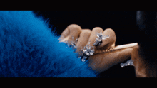 a woman wearing a blue fur coat holds a phone