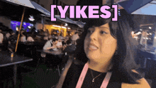 a woman stands in front of a crowd with the word yikes above her