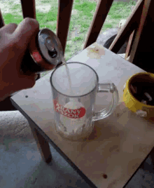 a person is pouring a drink from a can into a glass mug that says frank azzor