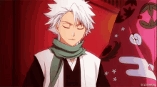 a man with white hair and a green scarf around his neck is standing in front of a red wall .