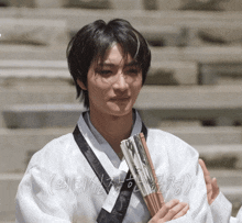 a man in a white kimono is holding a fan in his hands