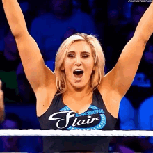a woman is standing in a wrestling ring with her arms in the air and her mouth open .