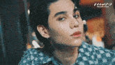 a close up of a young man 's face with a checkered shirt on