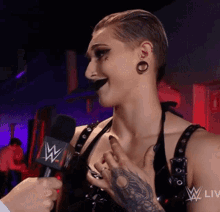 a woman with a tattoo on her arm is being interviewed by a man with a w logo on the microphone