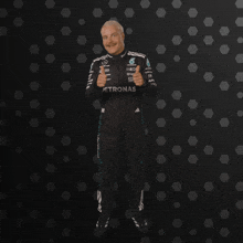 a man in a petronas suit stands in front of a dark background