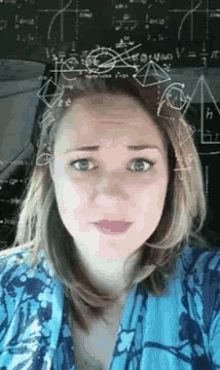a woman is taking a selfie in front of a blackboard with mathematical equations .