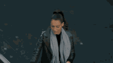 a woman wearing a scarf and a leather jacket walking down stairs