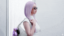 a doll with purple hair is standing next to a silver bag